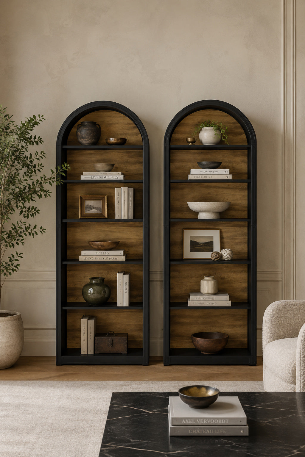 Two tall arched wooden bookshelves with black metal frames, styled with books, ceramic vases, bowls, and small framed art in a warm beige living room setting.