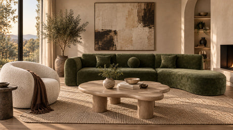 Green curved sectional sofa, rounded cream chair and organic-shaped wood coffee table in a warm modern living room