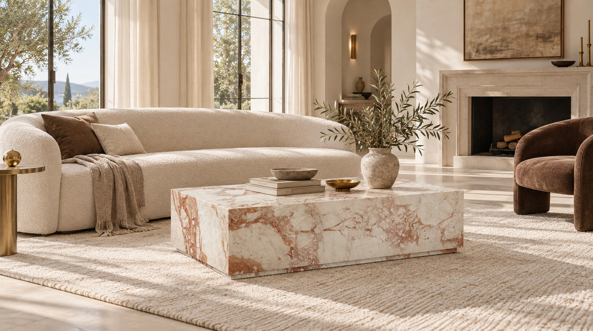 Cream and blush marble coffee table in an elegant neutral living room with curved bouclé seating.