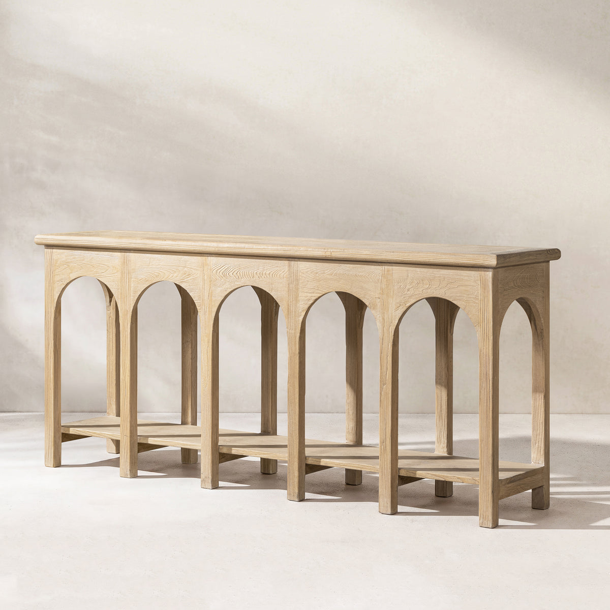 Natural Reclaimed Elm Console Table with Arched Base — against a living-room wall