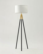Floor lamp with black tripod base and white shade on a light gray background
