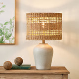 Gray Ceramic Table Lamp with Woven Rattan Shade — lit on a console