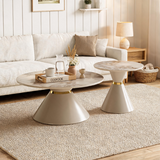 Two modern round coffee tables with beige and white stone tops and tapered pedestal bases in a warm, neutral living room setting.