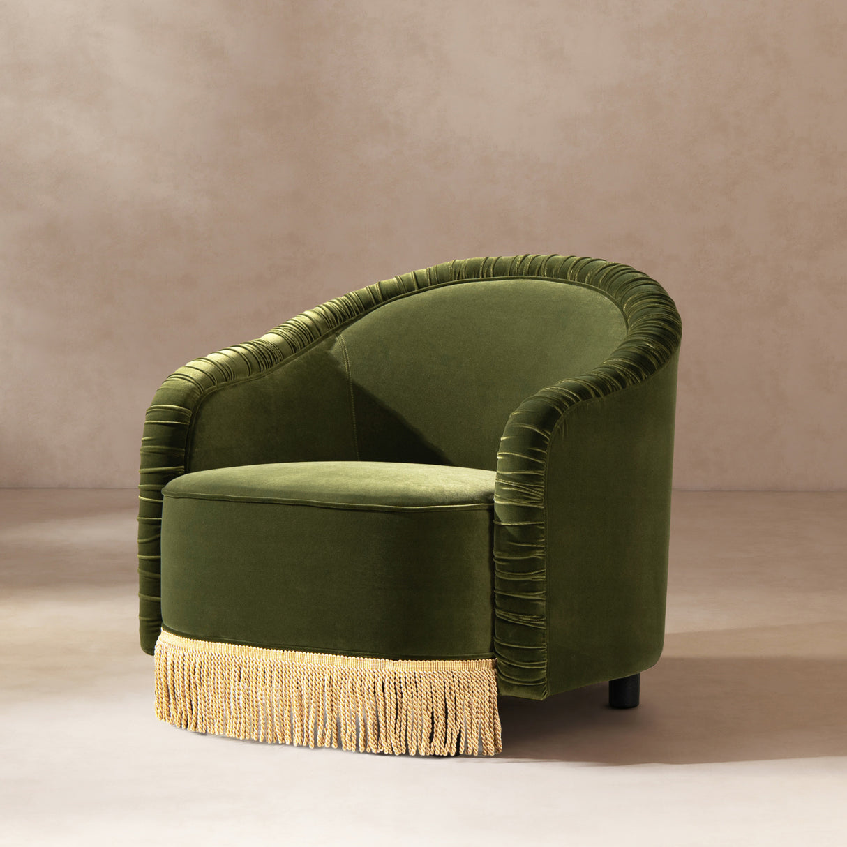 Green velvet armchair with fringe on a beige background