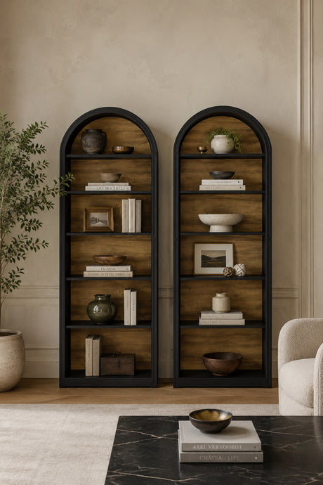 Two tall arched wooden bookshelves with black metal frames, styled with books, ceramic vases, bowls, and small framed art in a warm beige living room setting.
