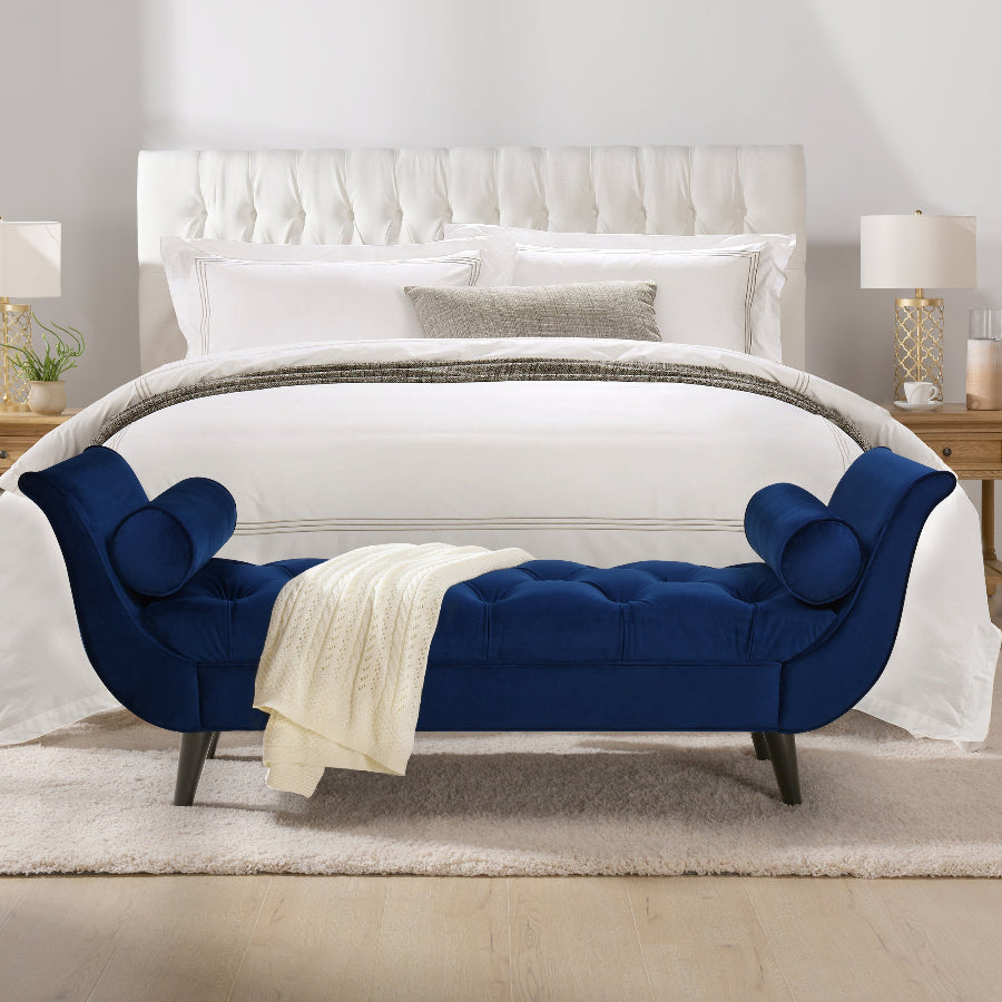 Blue tufted bench in front of a white bed with white bedding