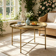 A round brass coffee table with a decorative top and slim metal legs.