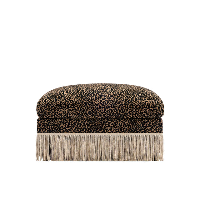A square ottoman with a leopard print velvet top and a long fringe base, shown against a plain white background.