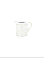 White ceramic creamer with gold accents on a white background