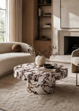 A round coffee table with a white marble base featuring dark brown and black veining.